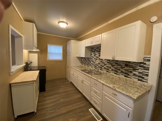 kitchen featuring visible vents, dark wood-style flooring, crown molding, white cabinetry, and a sink