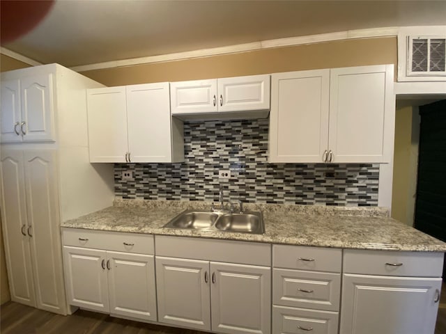 kitchen with tasteful backsplash, visible vents, white cabinets, and a sink