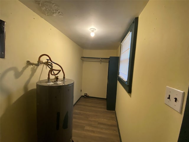 hallway featuring water heater, baseboards, and wood finished floors