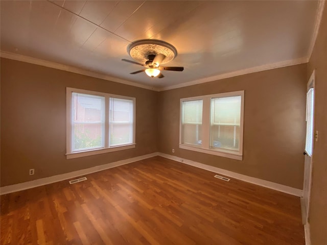 spare room featuring baseboards, crown molding, visible vents, and wood finished floors