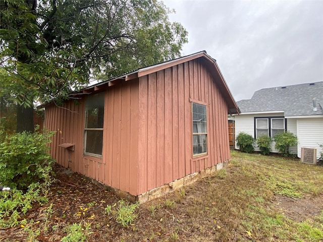 view of property exterior with central air condition unit, board and batten siding, and a yard