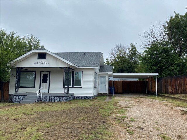 view of front facade featuring a front lawn, a carport, and covered porch