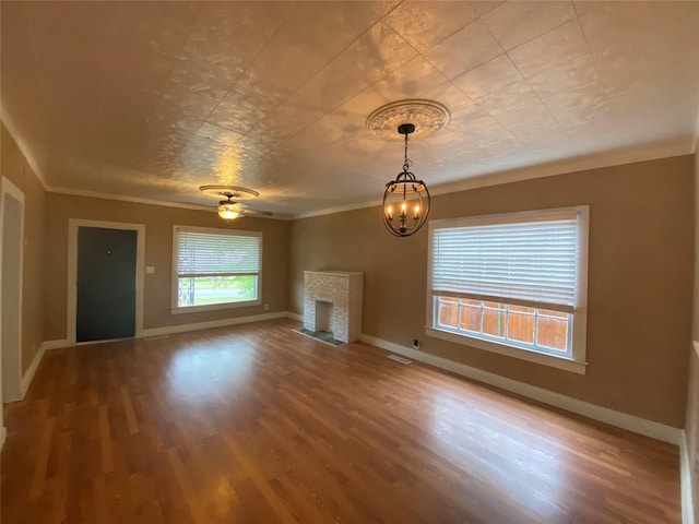 unfurnished living room featuring baseboards, ornamental molding, wood finished floors, a fireplace, and ceiling fan with notable chandelier