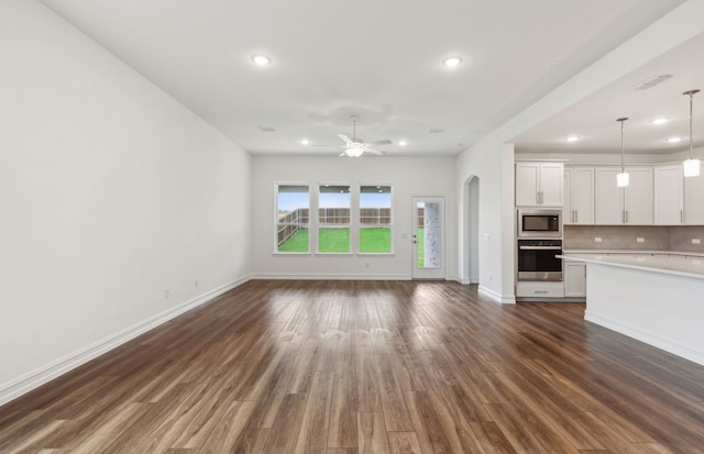 unfurnished living room with dark hardwood / wood-style flooring and ceiling fan