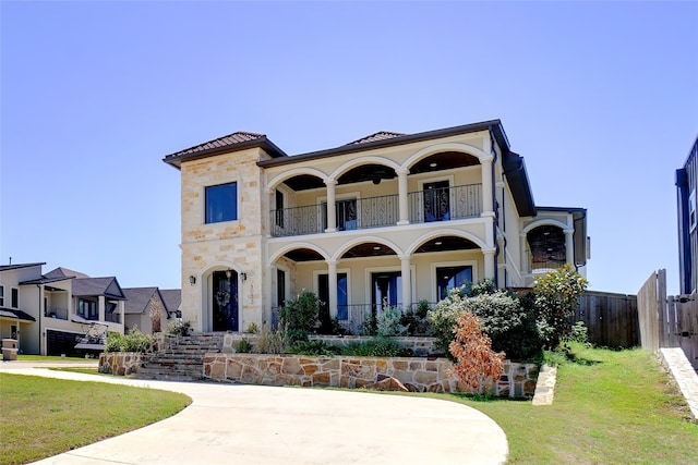 mediterranean / spanish-style house featuring a balcony and a front yard