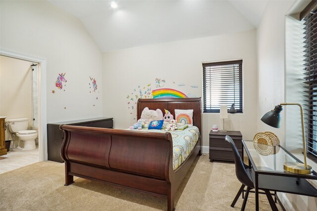 bedroom with lofted ceiling, light colored carpet, and ensuite bath