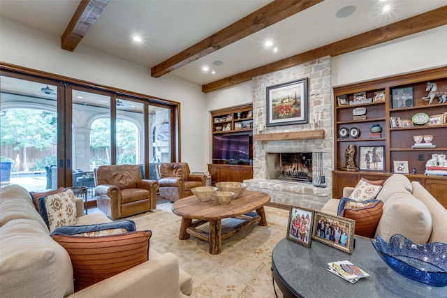 living room featuring built in shelves, a stone fireplace, and beam ceiling