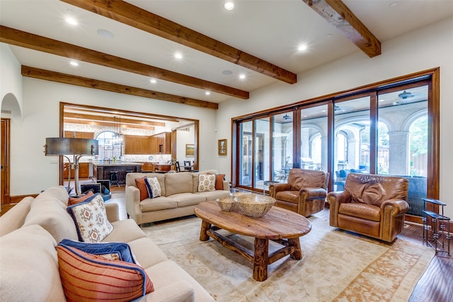 living room with light hardwood / wood-style flooring, beam ceiling, and a notable chandelier