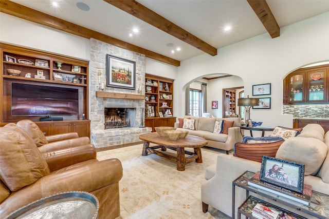 living room with built in features, a fireplace, and beamed ceiling