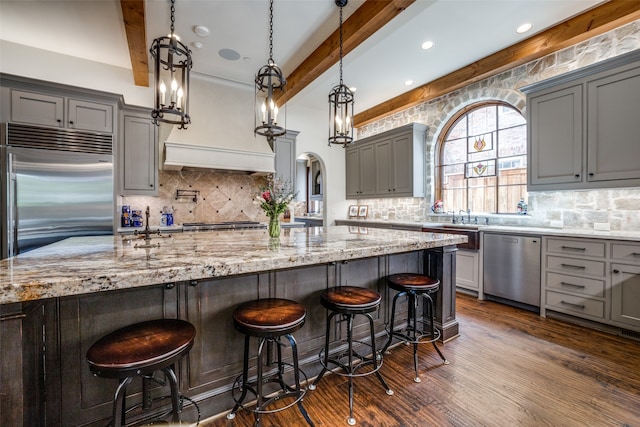 kitchen featuring dark hardwood / wood-style floors, beamed ceiling, a large island, and appliances with stainless steel finishes