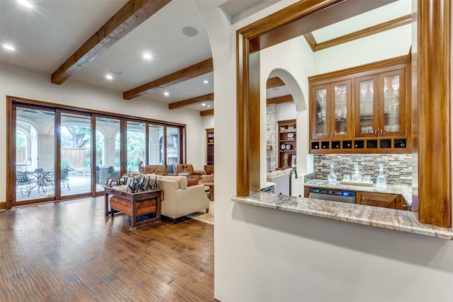 kitchen with light stone countertops, dishwasher, beam ceiling, decorative backsplash, and hardwood / wood-style flooring