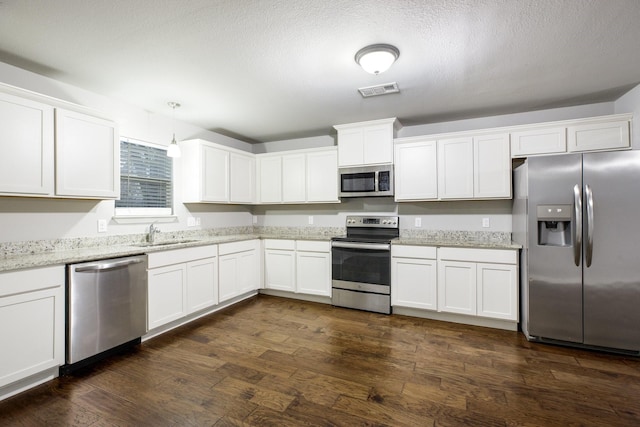 kitchen with decorative light fixtures, dark hardwood / wood-style flooring, stainless steel appliances, light stone countertops, and white cabinets