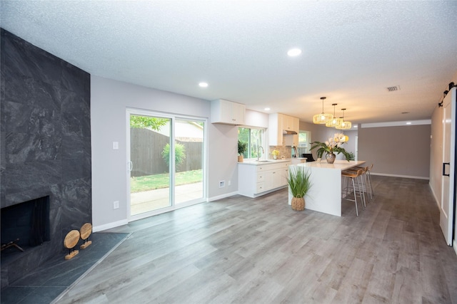 kitchen with a textured ceiling, a fireplace, light countertops, and wood finished floors