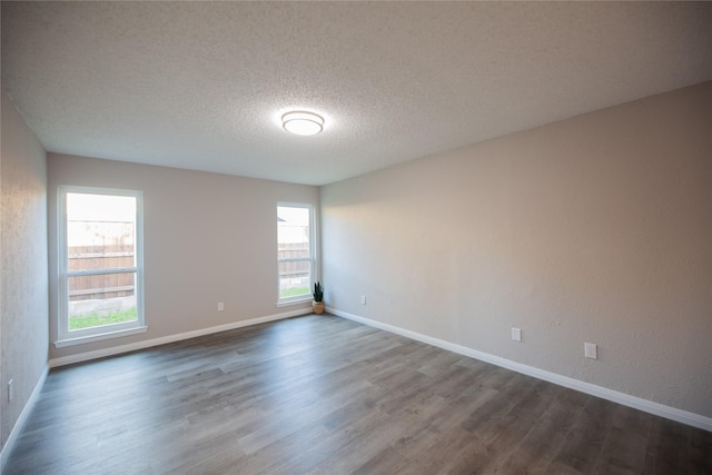 empty room featuring dark wood-style flooring, a textured ceiling, and baseboards