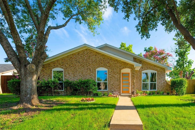 view of front of house featuring a front yard, fence, and brick siding