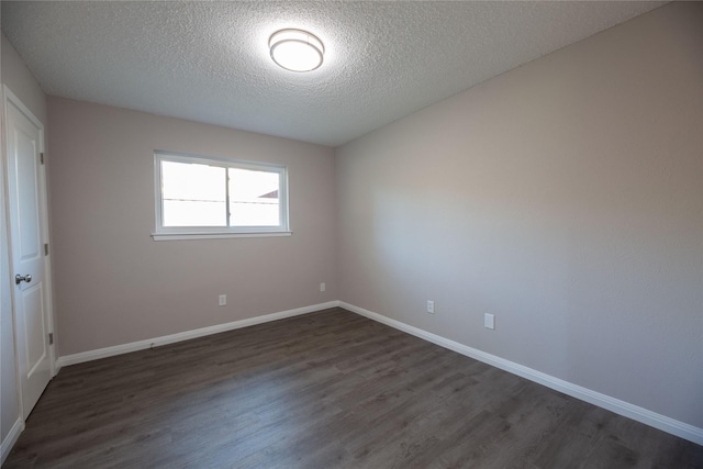 empty room with dark wood-style flooring, a textured ceiling, and baseboards