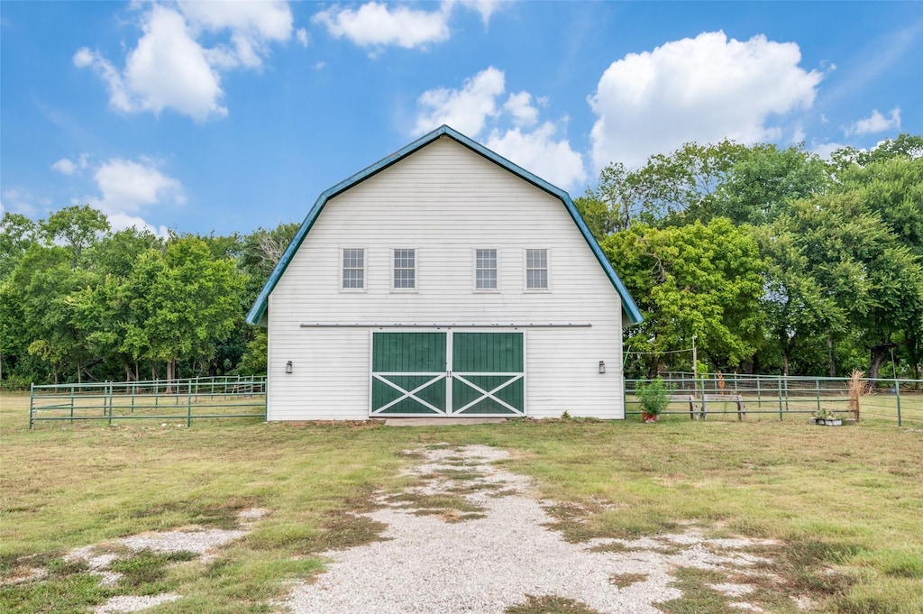 view of barn with fence, a lawn, and driveway