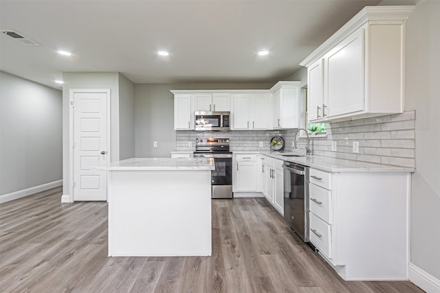 kitchen with light hardwood / wood-style flooring, a center island, sink, appliances with stainless steel finishes, and white cabinets