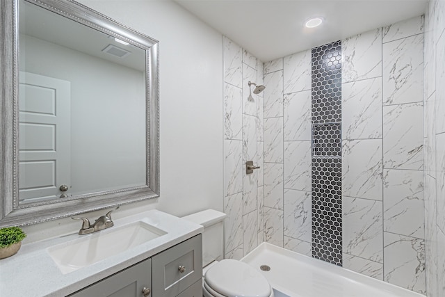 bathroom with vanity, toilet, and a tile shower