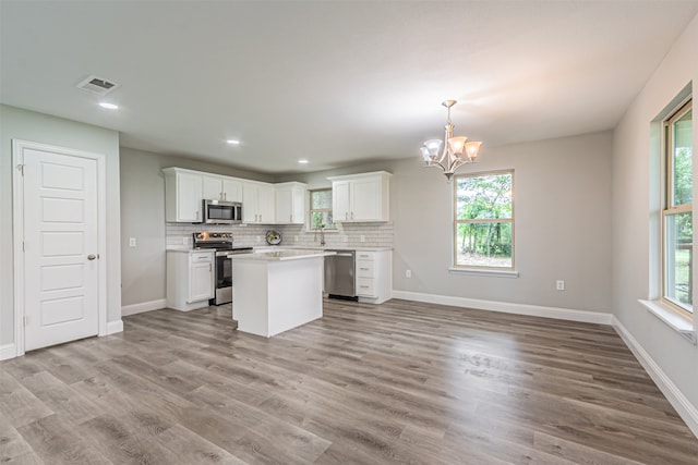 kitchen featuring appliances with stainless steel finishes, pendant lighting, white cabinetry, and light hardwood / wood-style flooring