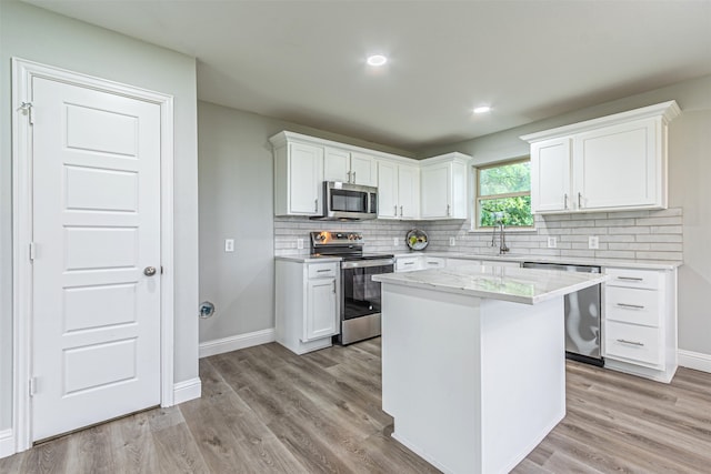 kitchen with light hardwood / wood-style flooring, sink, a center island, appliances with stainless steel finishes, and white cabinets