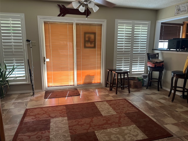 doorway to outside with beam ceiling, ceiling fan, and a textured ceiling