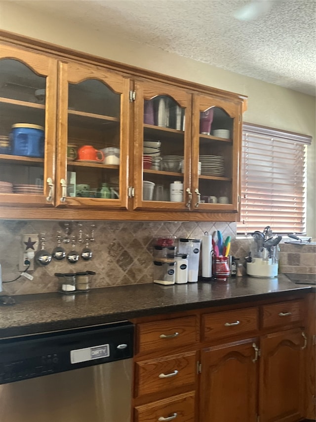 kitchen with stainless steel dishwasher, a textured ceiling, and tasteful backsplash