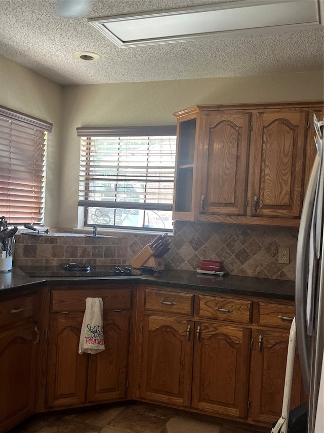 kitchen with tile patterned flooring, stainless steel refrigerator, and tasteful backsplash