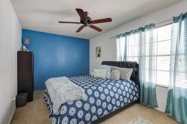 bedroom with ceiling fan, light carpet, and a textured ceiling