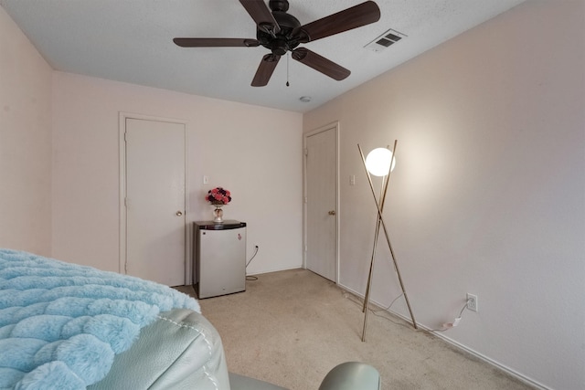 bedroom with light colored carpet, ceiling fan, and white refrigerator