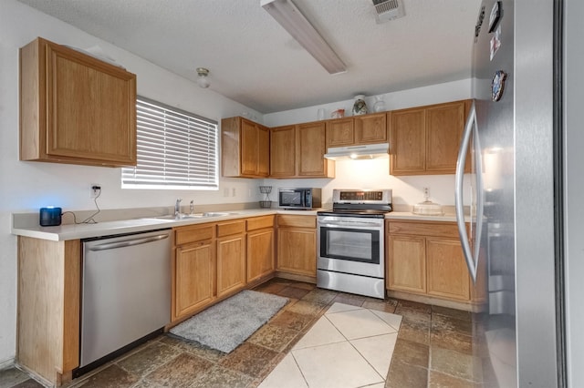 kitchen featuring a textured ceiling, stainless steel appliances, and sink