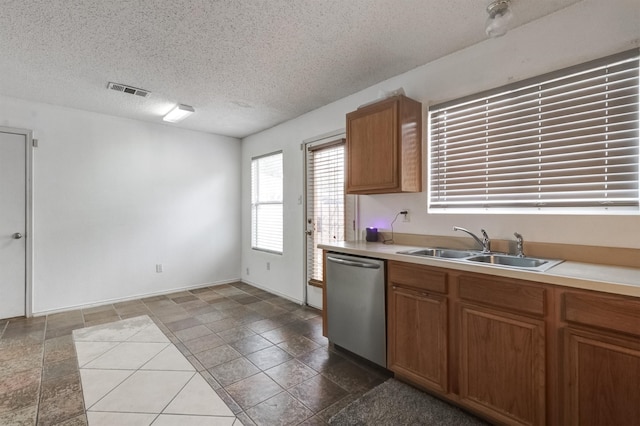 kitchen with a textured ceiling, stainless steel dishwasher, and sink