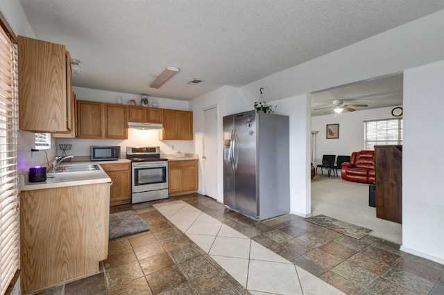 kitchen with a textured ceiling, stainless steel appliances, sink, and ceiling fan