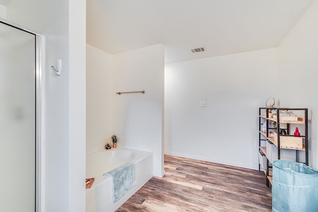 bathroom with independent shower and bath and hardwood / wood-style floors