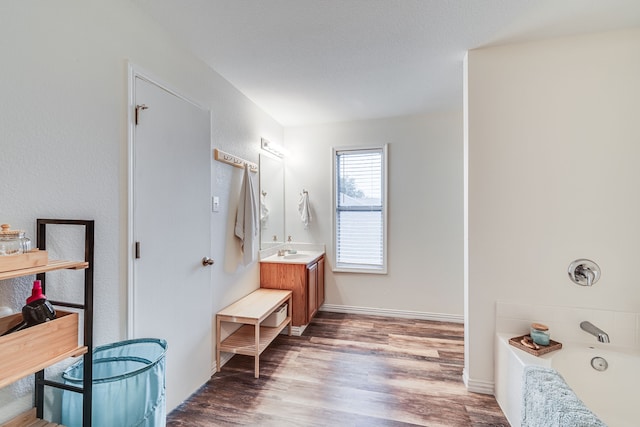 bathroom featuring wood-type flooring, vanity, and a tub to relax in