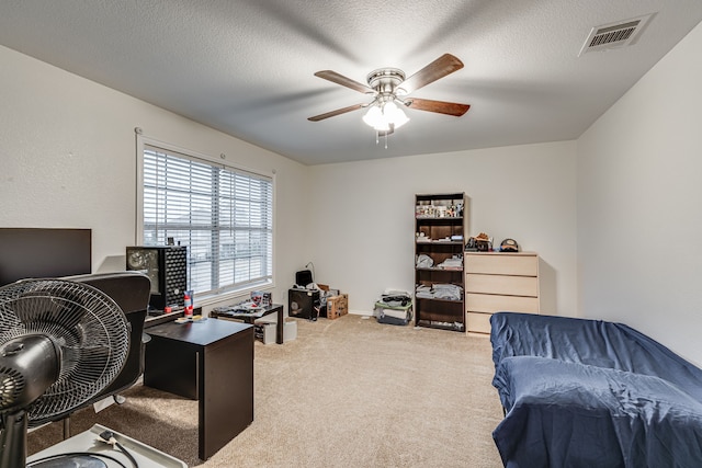 carpeted home office with a textured ceiling and ceiling fan