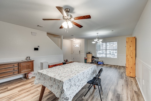 dining room with ceiling fan with notable chandelier and light hardwood / wood-style floors