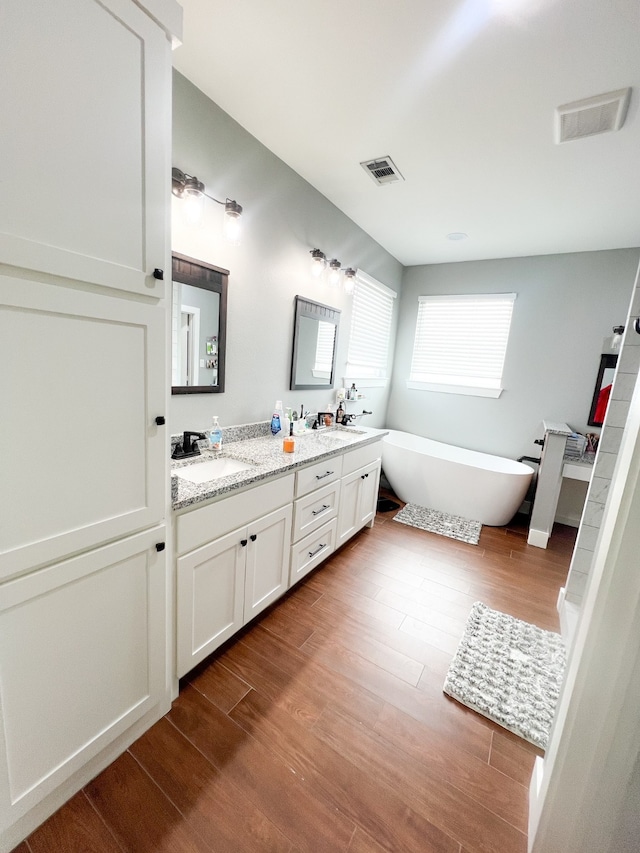 bathroom featuring vanity, hardwood / wood-style floors, and a tub