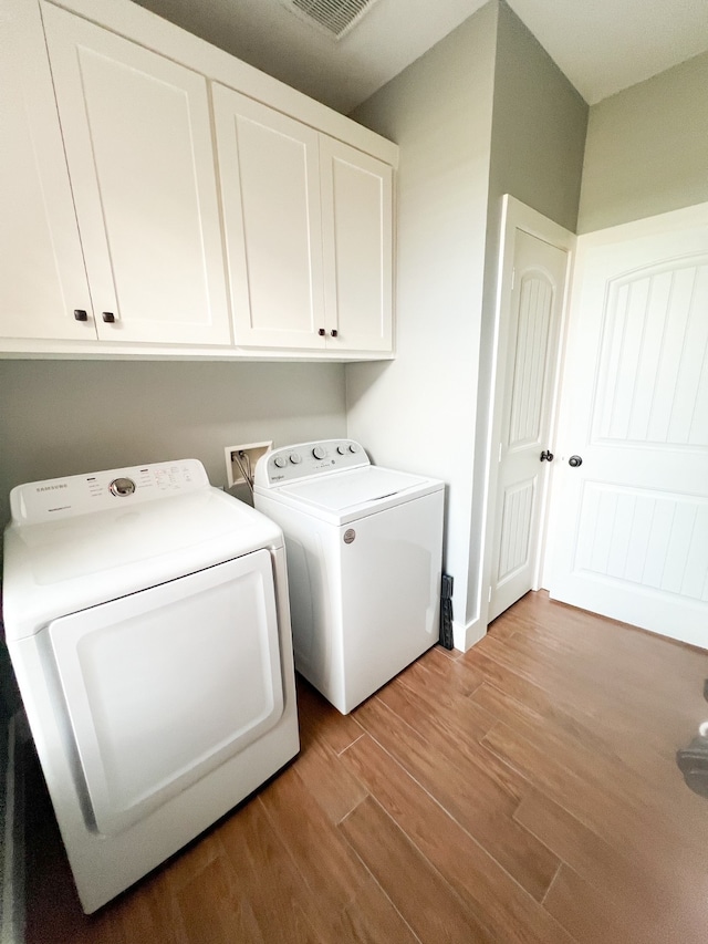 laundry room with light hardwood / wood-style flooring, washing machine and dryer, and cabinets