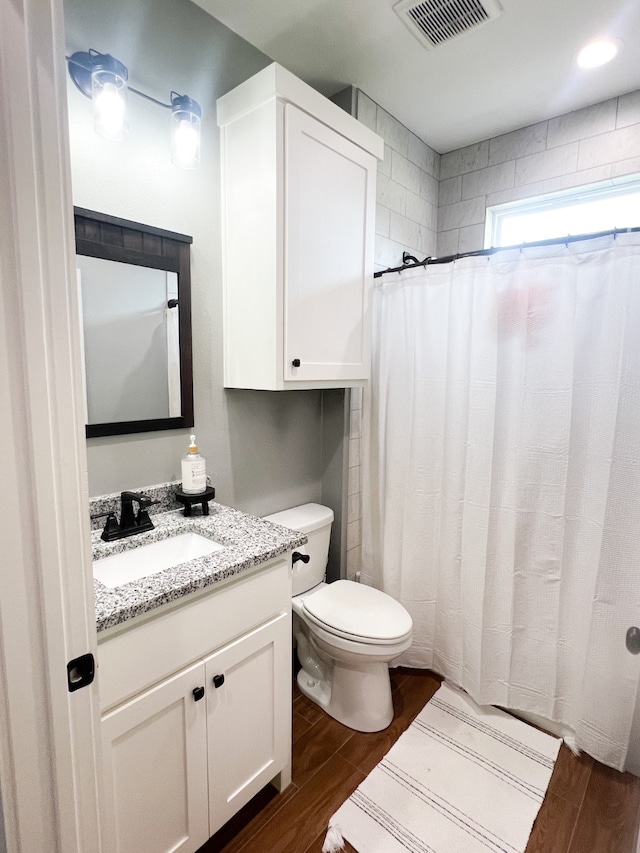 bathroom featuring vanity, toilet, hardwood / wood-style flooring, and walk in shower