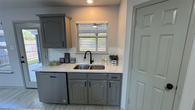 kitchen featuring light hardwood / wood-style flooring, gray cabinetry, dishwasher, and sink