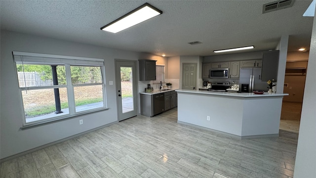 kitchen featuring stainless steel appliances, sink, gray cabinets, and light hardwood / wood-style floors