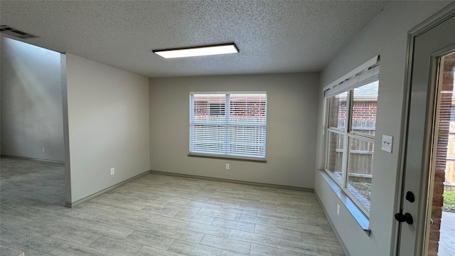 unfurnished room featuring a textured ceiling and light hardwood / wood-style floors