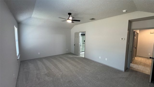 carpeted empty room with lofted ceiling, ceiling fan, and a textured ceiling