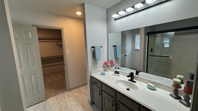 bathroom featuring a shower with door, vanity, hardwood / wood-style flooring, and a textured ceiling