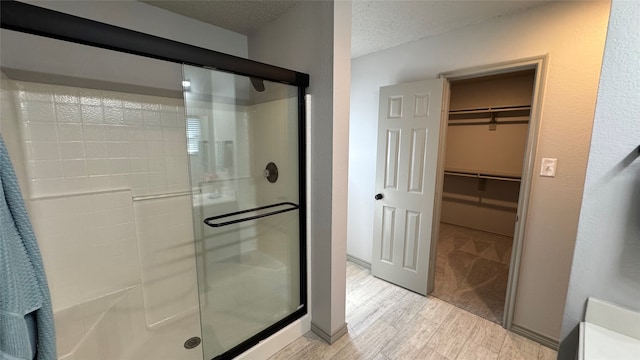 bathroom featuring wood-type flooring, an enclosed shower, and a textured ceiling