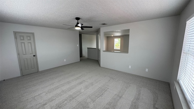 empty room with a textured ceiling, ceiling fan, and light carpet