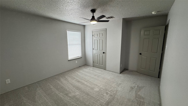 unfurnished bedroom with a closet, ceiling fan, light carpet, and a textured ceiling