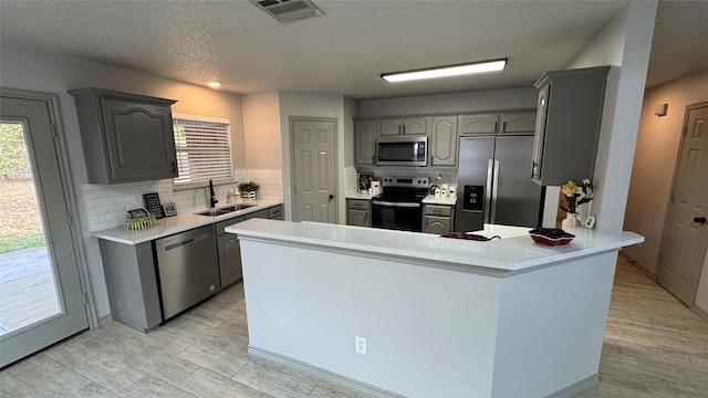 kitchen with a healthy amount of sunlight, gray cabinetry, sink, and appliances with stainless steel finishes