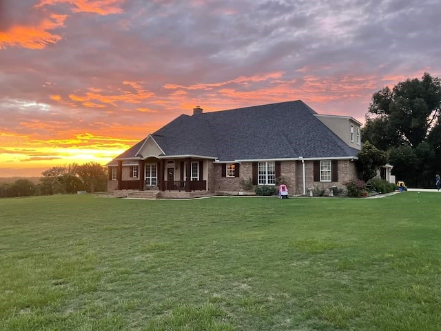 back house at dusk featuring a lawn